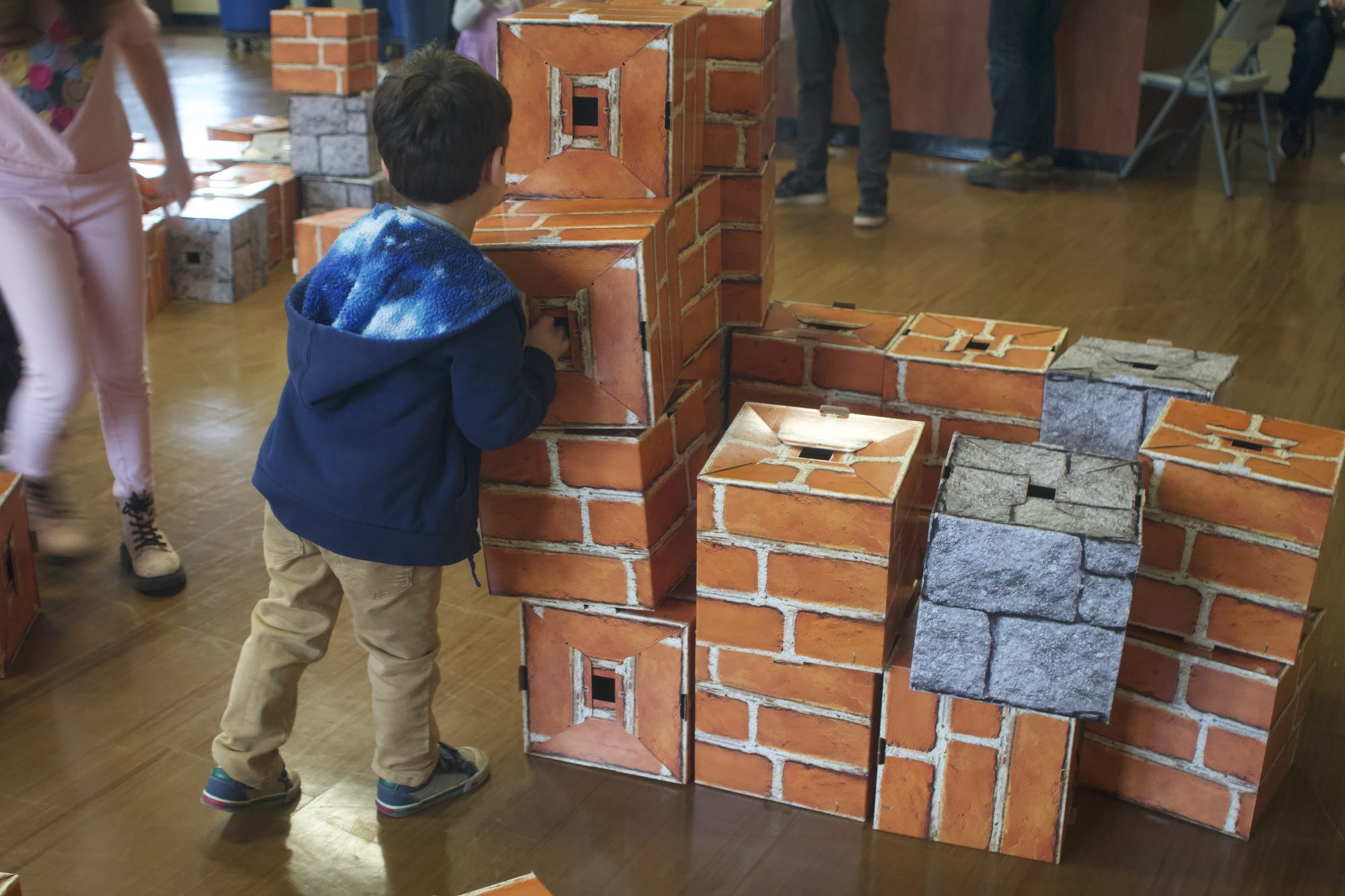 A child adding a block to a growing structure