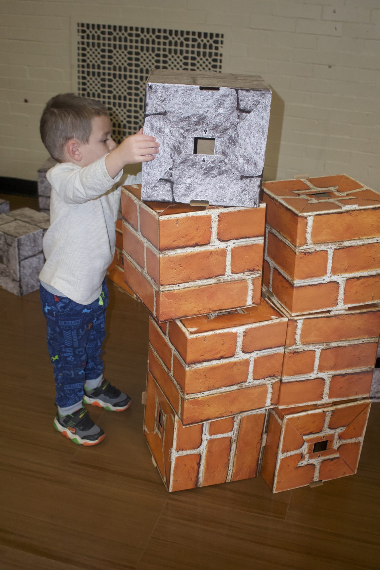 A child placing a giant block on a wall