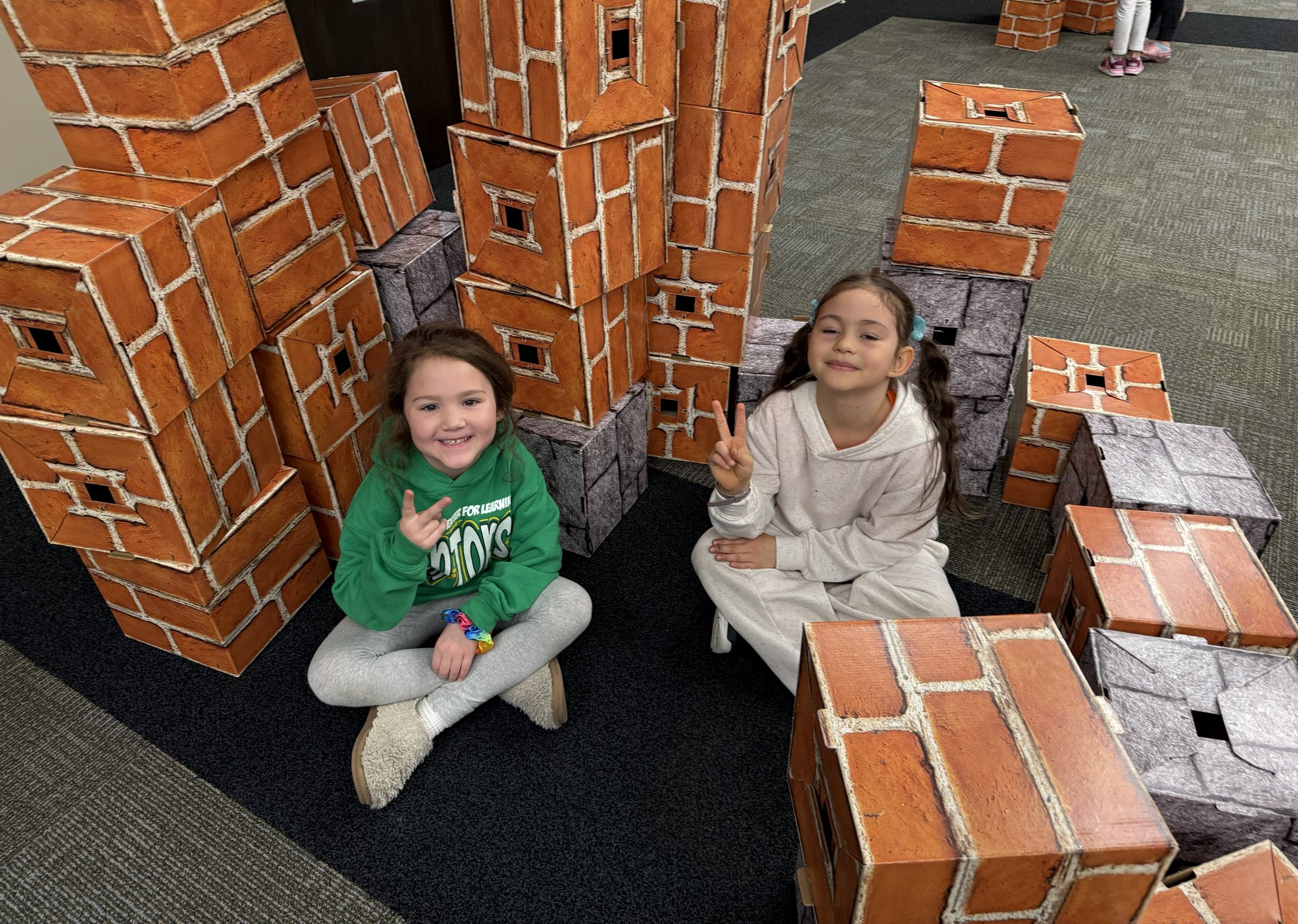 Two children sitting in front of the towers they built