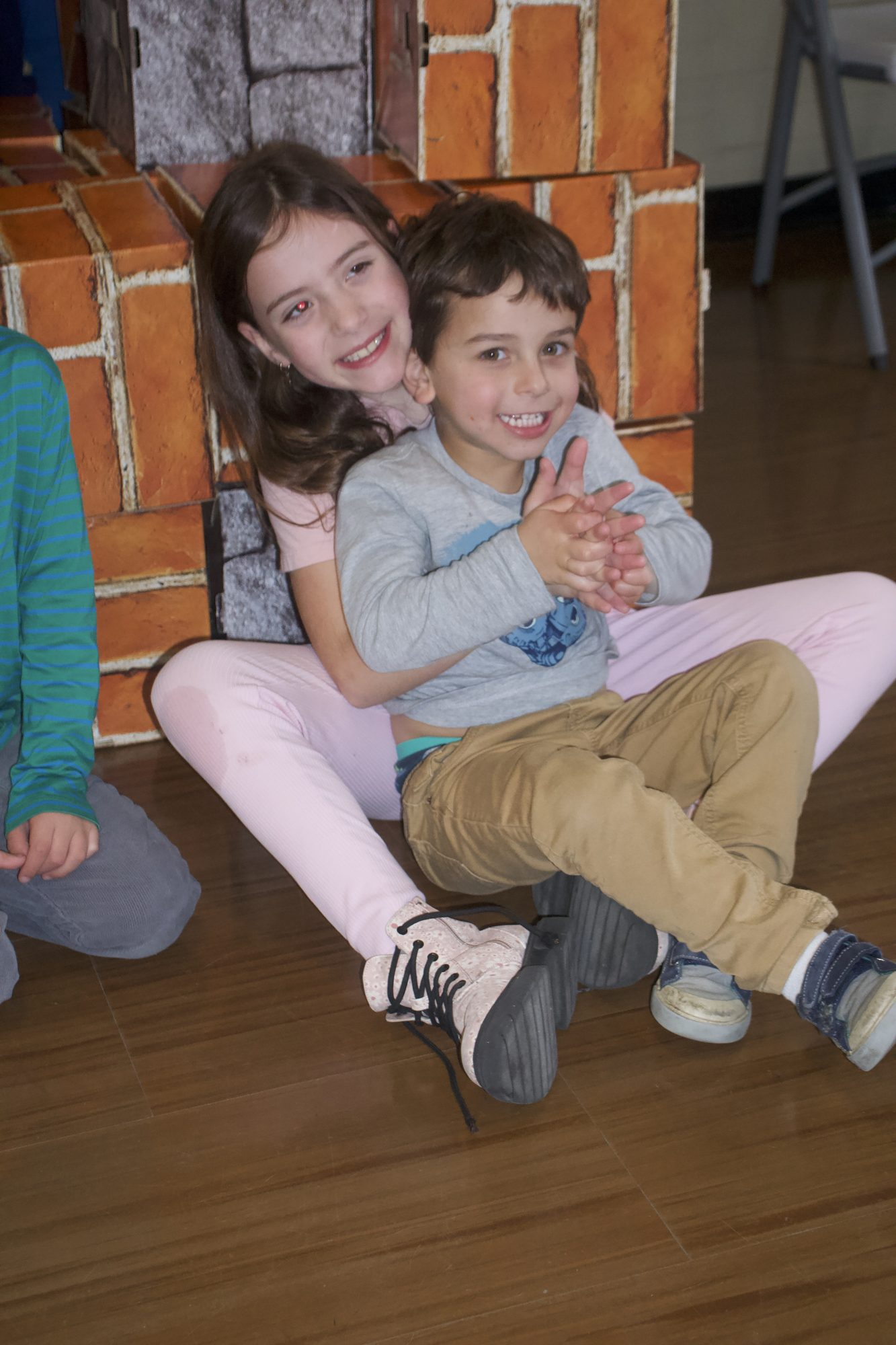 Two children sitting in the doorway of their block fort